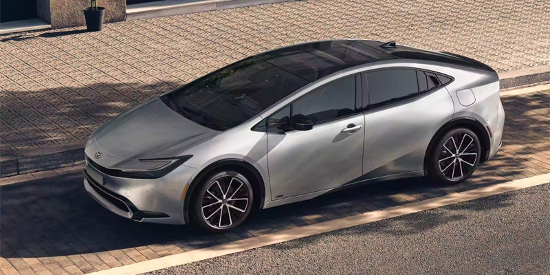 A 2024 Toyota Prius driving under shady trees in Bishop, CA